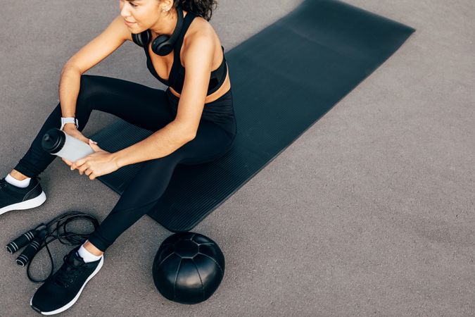 Athletic woman holding water bottle on yoga mat