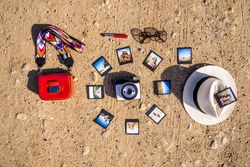 Stylish accessories and instant photos on sandy ground