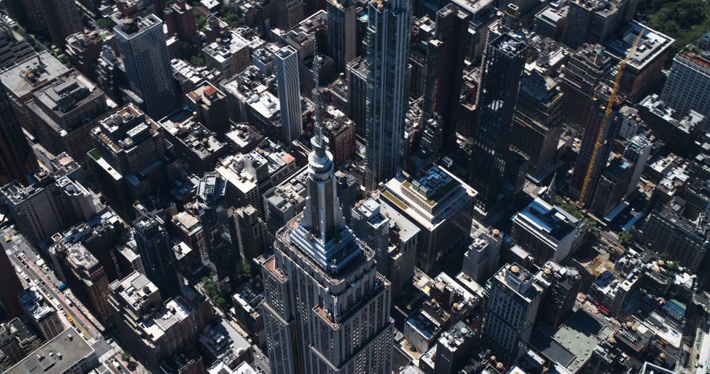 Aerial Footage of New York City and Manhattan Panoramic Skyline with Iconic Empire State Building. Helicopter View of the Cityscape from Above with Towering Tourist Attraction