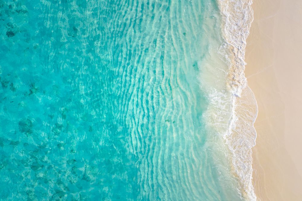 Aerial shot of beautiful clear blue water coming up on a beach