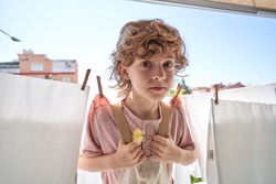 Funny boy hanging himself up on clothesline
