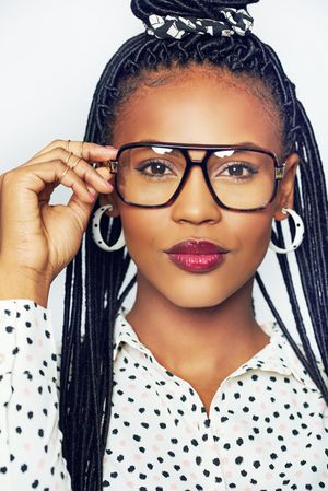 Portrait of happy and fashionable woman adjusting her glasses