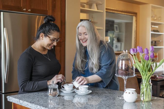 Smiling women preparing hot tea at home