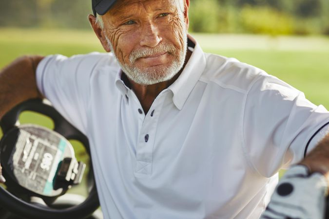 Grey haired man relaxing in golf cart