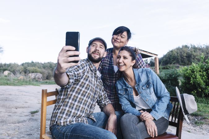Three friends sitting outdoors and taking a selfie