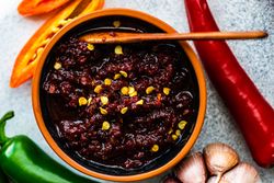 Top view of traditional Georgian sauce Adjika with spicy peppers and served with wooden spoon