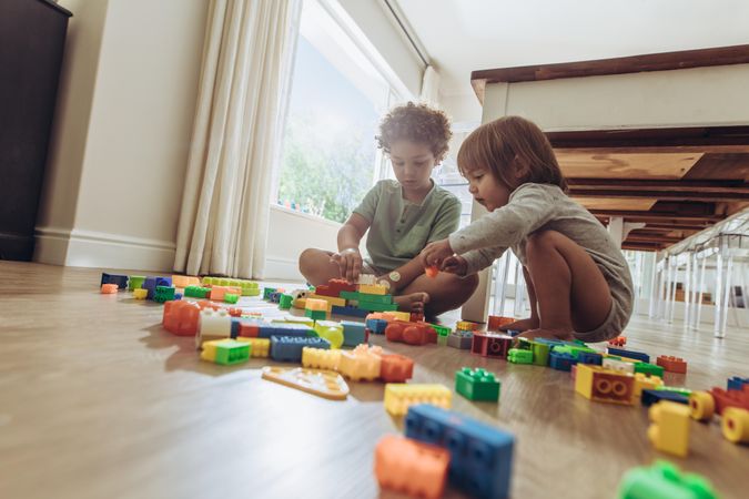 Two children sitting on floor and playing with building blocks