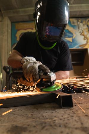 Male worker using electric grinder in workshop