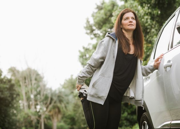 Woman stretching near car in park