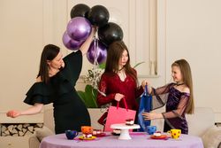 Teen holding gift bag with woman and young girl