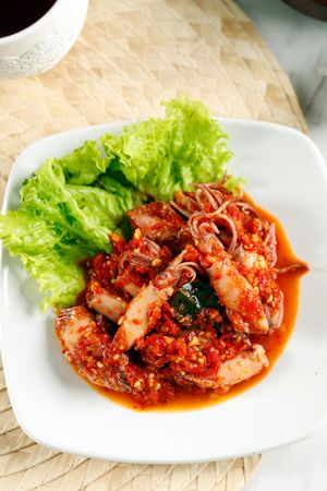 Spicy salted squid dish on placemat, vertical
