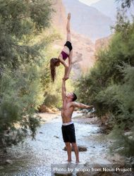 Man holding woman doing split in the air in river 5rBy15