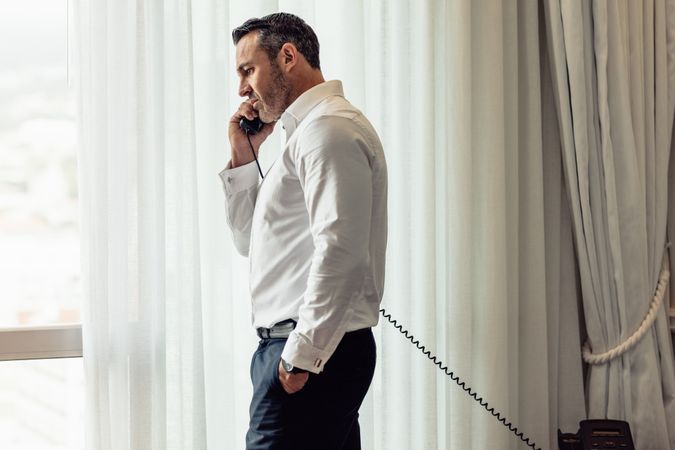 Businessman making call on landline from hotel room