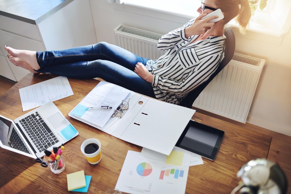 Woman leaning back at her home desk while taking a call