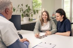 Doctor and couple reviewing ultrasound pictures at a clinic.