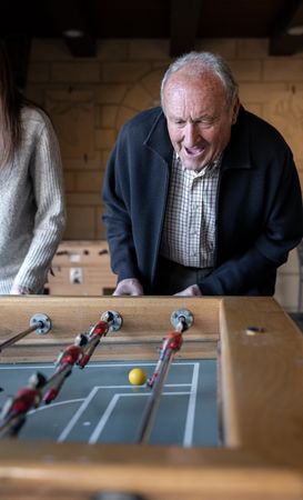A granddaugther and his grandfather are playing table football game and having fun together