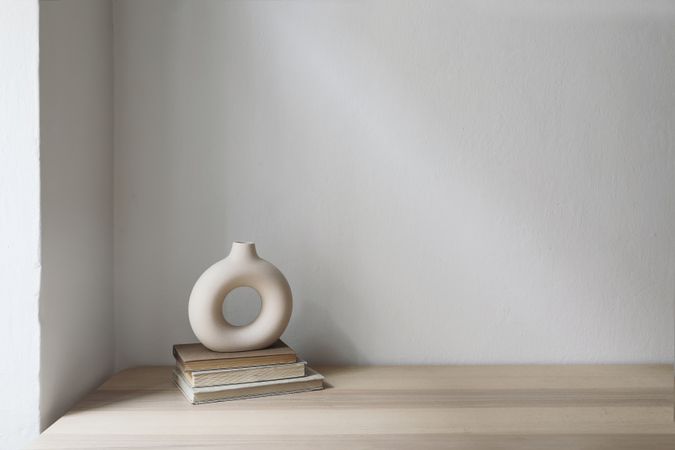 Elegant neutral still life with modern ceramic vase on old books. Wooden table, desk