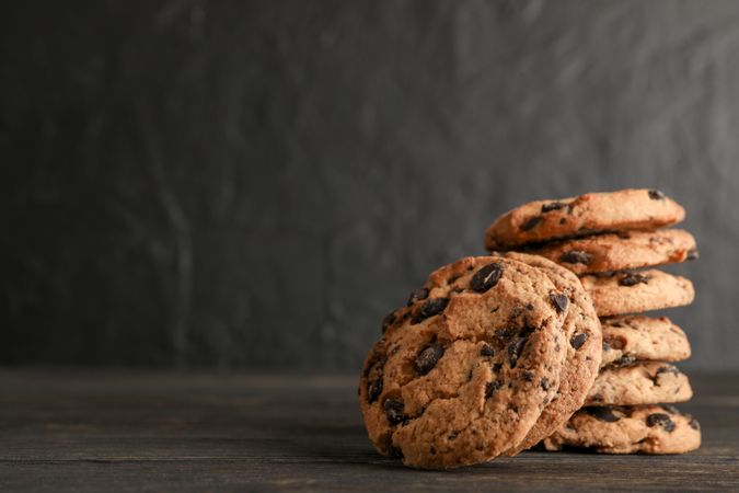 Stack of tasty chocolate chip cookies on wooden background. Space for text