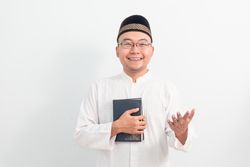 Asian Muslim man welcoming and holding quran during Ramadan