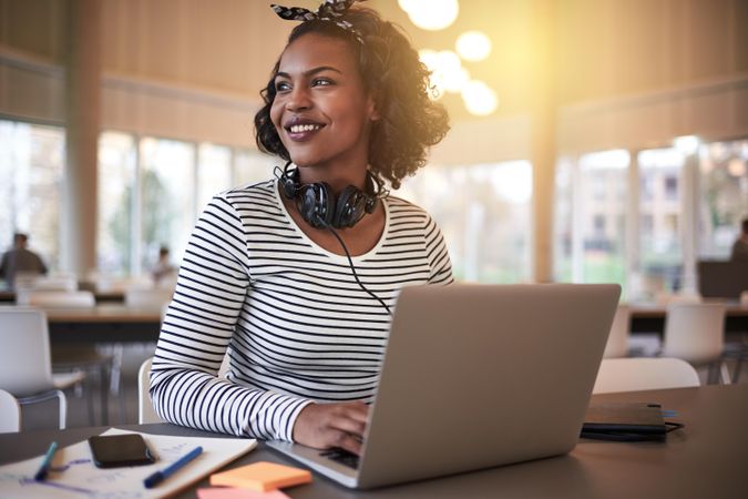 Woman working on her laptop with headphones in public library