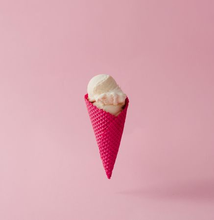 Vanilla ice cream in pink waffle cone on pink pastel background