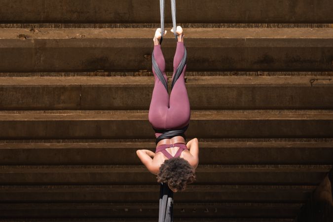 Slim woman doing aerial yoga in city