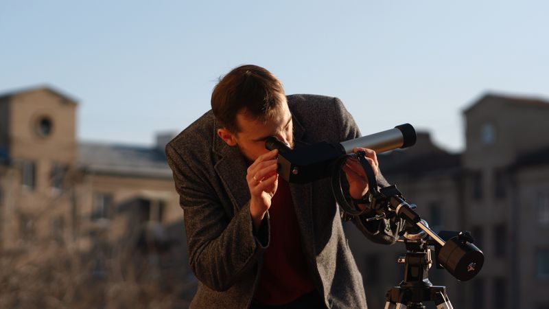 Man in grey coat carefully aligns telescope for solar observation