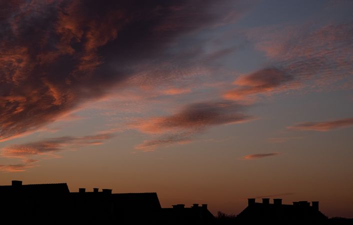 Orange blue sky with clouds and roofs at dawn
