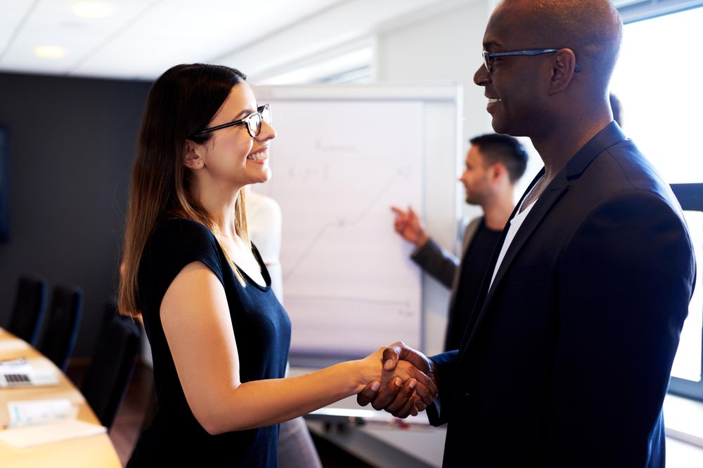 Male and female smiling and shaking hands in board room