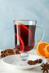 Mulled wine, orange and cinnamon on blue wooden background, space for text
