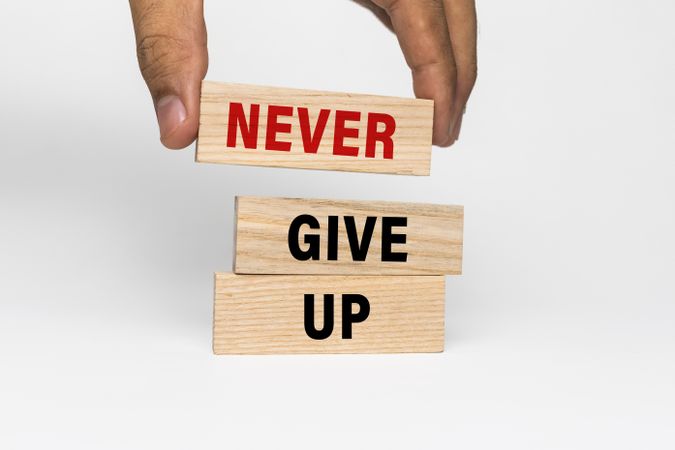 male hand put wooden blocks with never give up words