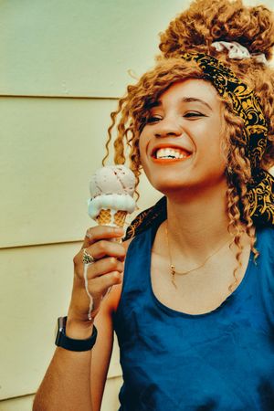 Vertical shot of smiling Black female enjoying an ice cream cone in the sun, copy space