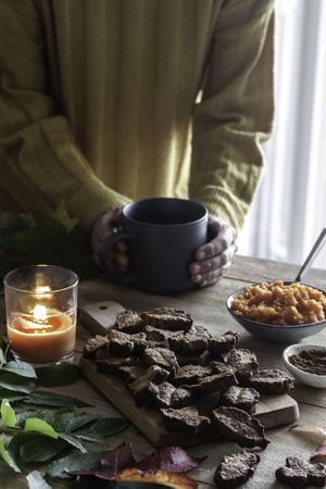 Crop person enjoying hot beverage and cookies