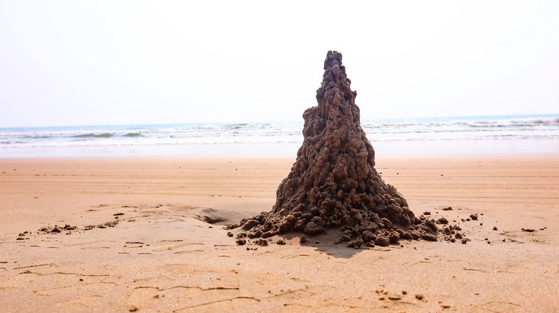 Drip sandcastle sculpture on a sunny beach shoreline