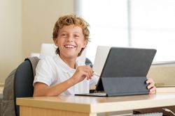 Happy pupil using tablet during lesson at school
