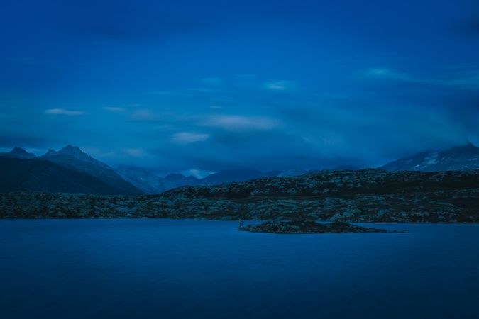 Calm lake in dark blue twilight surrounded by mountains