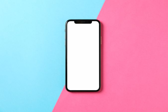 Phone with empty screen on two tone background, top view