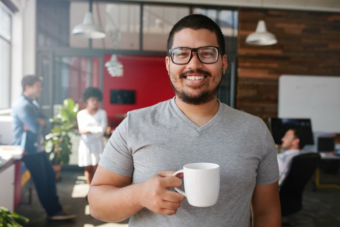 Happy man holding coffee cup at work