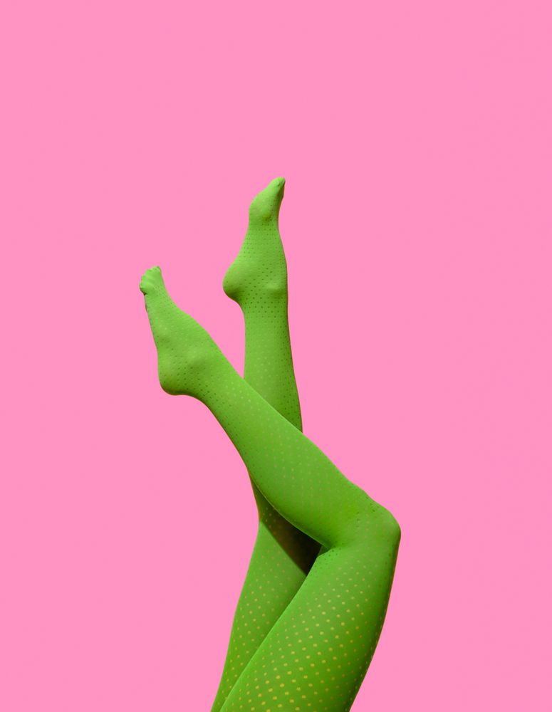 Female legs in green tights against a pink wall