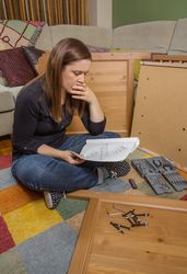 Woman reading instructions to assemble furniture