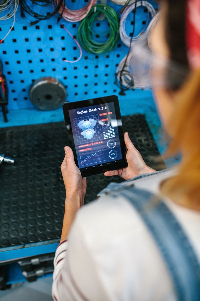 Mechanic woman checking engine diagnosis app in digital tablet