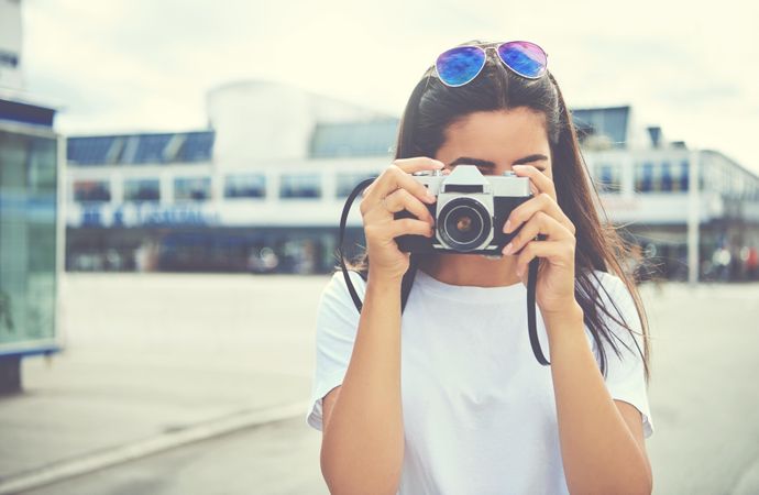 Brunette female with camera covering her face as she snaps a picture