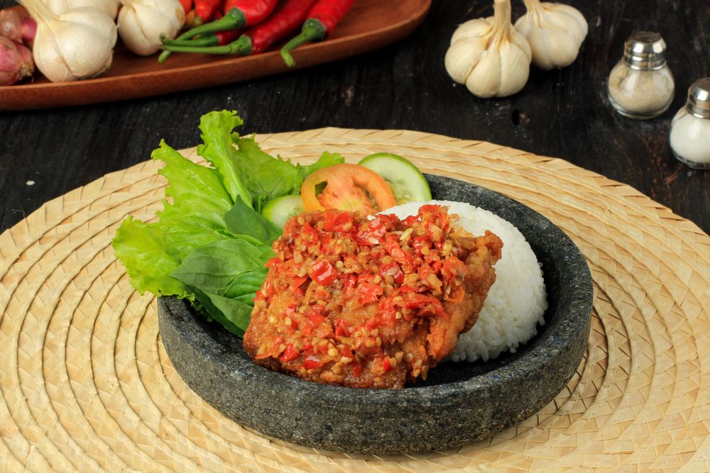 Plate of Ayam geprek, popular Indonesian street food made with smashed chicken in sambal bawang