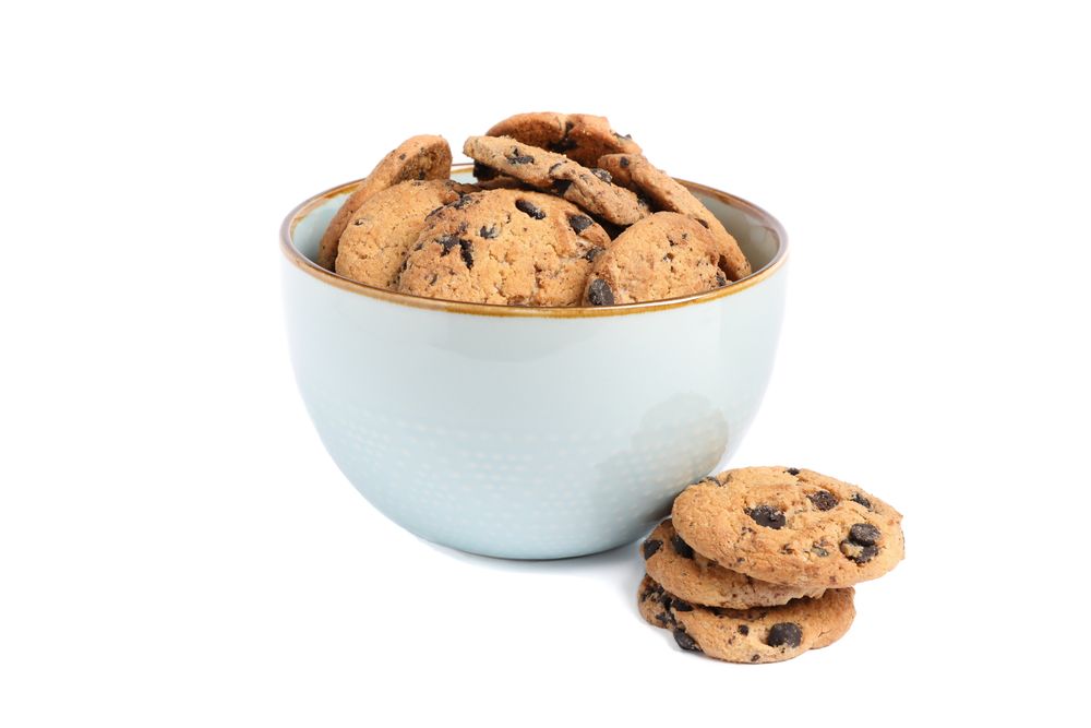 Bowl with tasty chocolate chip cookies on plain background
