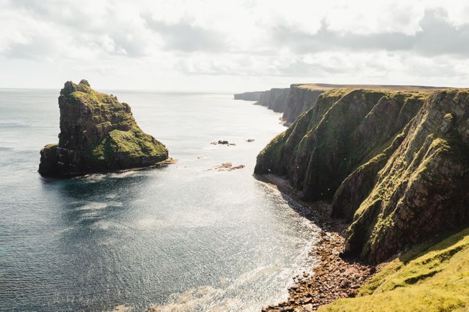 Rocky coast among tranquil ocean water in sunny day