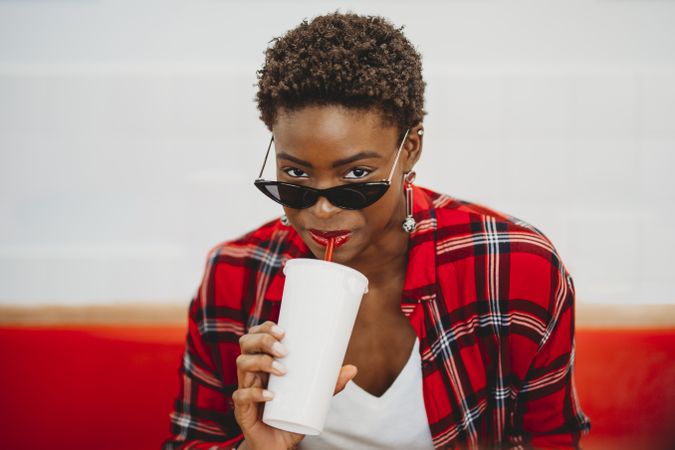 Stylish Black woman drinking from cup in cafe