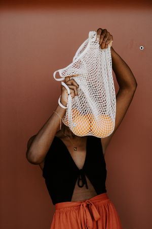 Woman holding a mesh bag of oranges