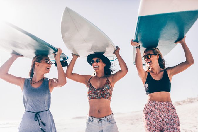 Group of young women holding surfboards overhead