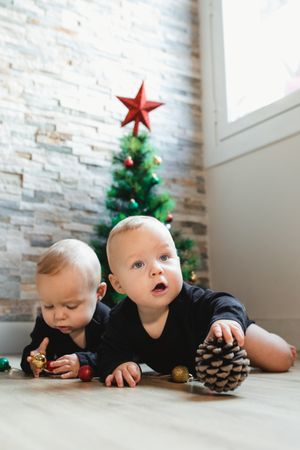 Twins on floor near Christmas tree