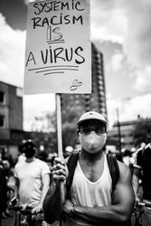 MONTREAL, QUEBEC, CANADA – June 7 2020- Man with arms crossed holding sign at a BLM protest